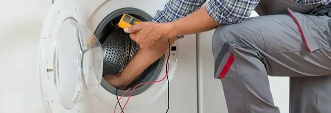 Dryer repair technician inspecting and repairing a clothes dryer in Colorado Springs, CO