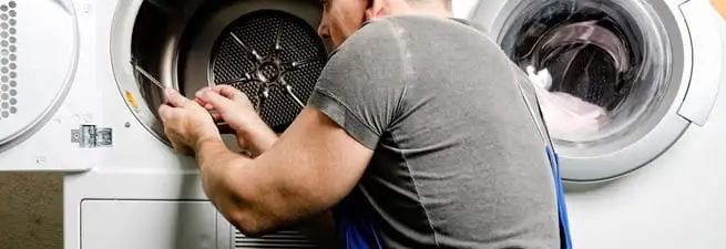 Dryer repair technician fixing a clothes dryer drum in Colorado Springs, CO