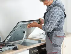 Appliance repair technician installing a built-in cooktop in Colorado Springs, CO