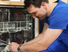 Dishwasher repair technician inspecting and servicing an open dishwasher in Colorado Springs, CO