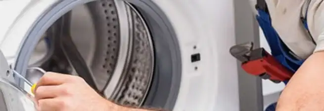 Appliance technician repairing a clothes dryer drum and internal parts in Colorado Springs, CO