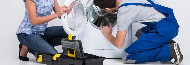 Washer repair technician inspecting a front-load washing machine with tools in Colorado Springs, CO