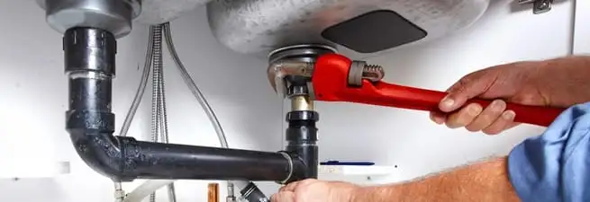 Garbage disposal repair technician tightening the sink drain and disposal connection in Colorado Springs, CO