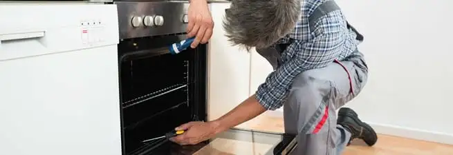 Oven repair technician inspecting and servicing an electric oven in Colorado Springs, CO