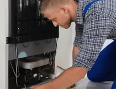 Refrigerator repair technician servicing the compressor and condenser area in Colorado Springs, CO