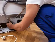 Appliance repair technician fixing refrigerator water line and connections in Colorado Springs, CO