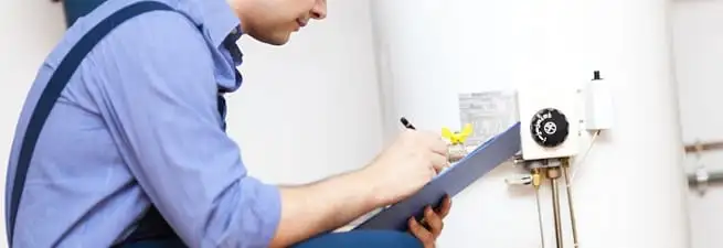 Water heater repair technician inspecting the unit and recording service notes in Colorado Springs, CO