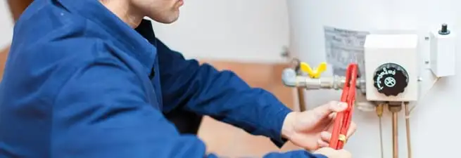 Water heater repair technician adjusting the temperature control and gas valve in Colorado Springs, CO